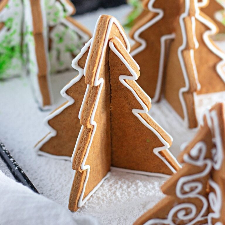 Featured photo of gingerbread Christmas tree cookies arranged in powdered sugar snow.