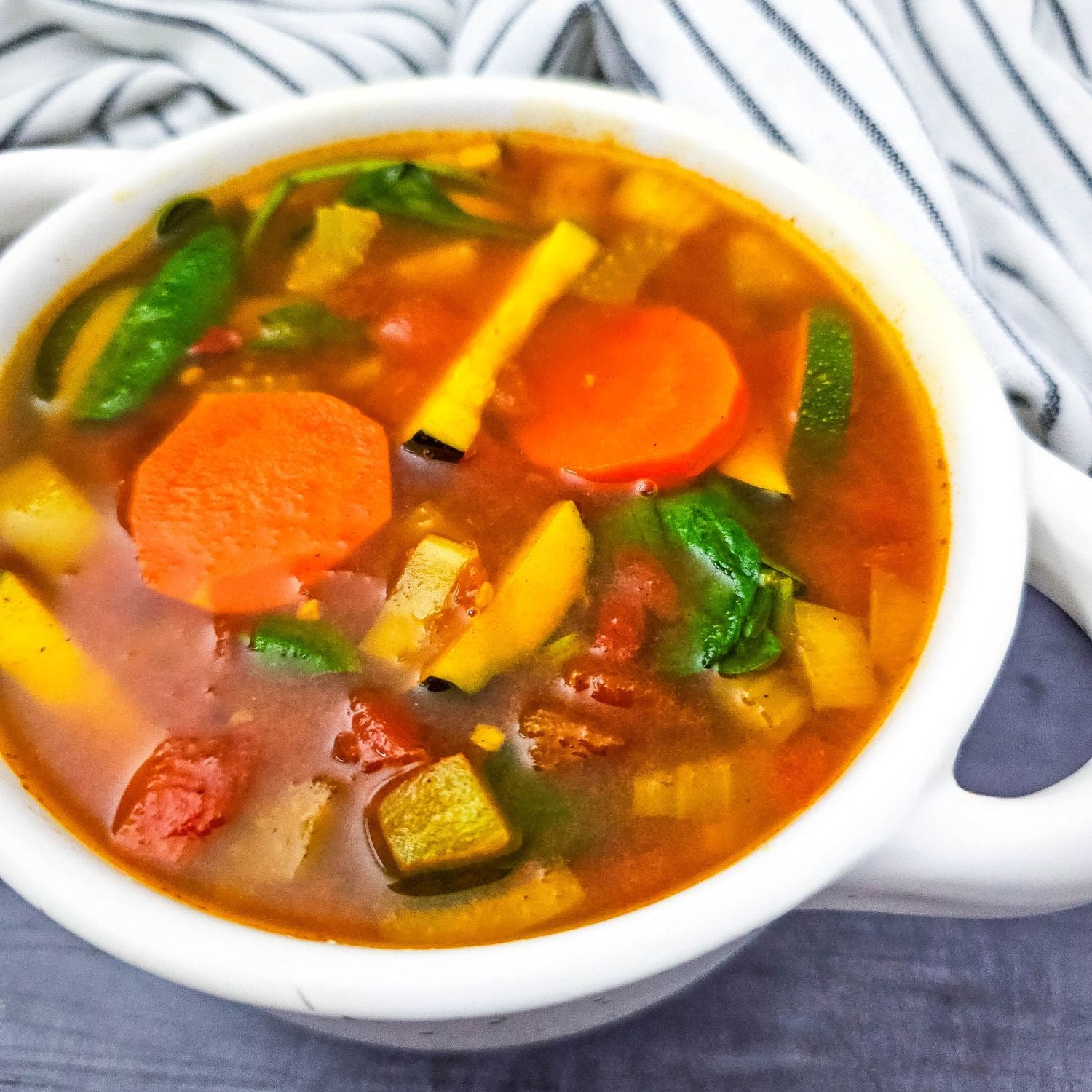 Warm Moroccan soup with carrots, zucchini, and greens in a ceramic bowl.