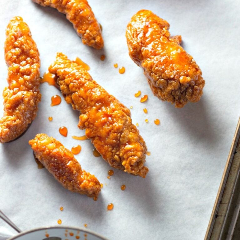 Crispy chicken strips covered in sticky sweet-spicy sauce on a plate
