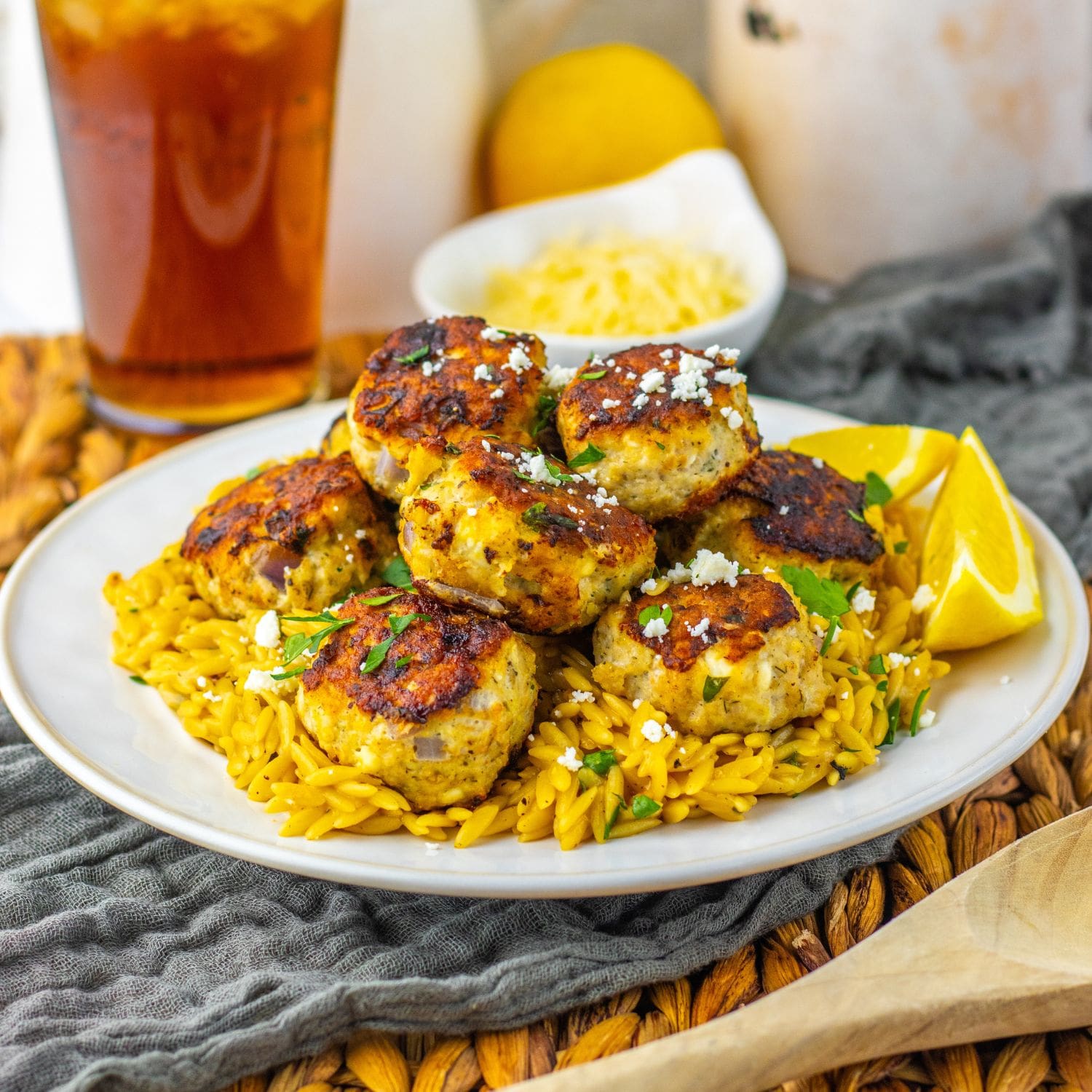 Hero shot of Greek chicken meatballs with lemon orzo pasta served with lemon wedges.