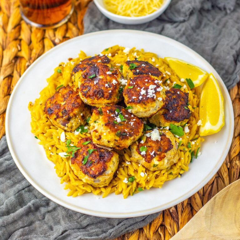 Recipe card photo of Greek chicken meatballs over lemon orzo pasta, styled with feta and parsley.