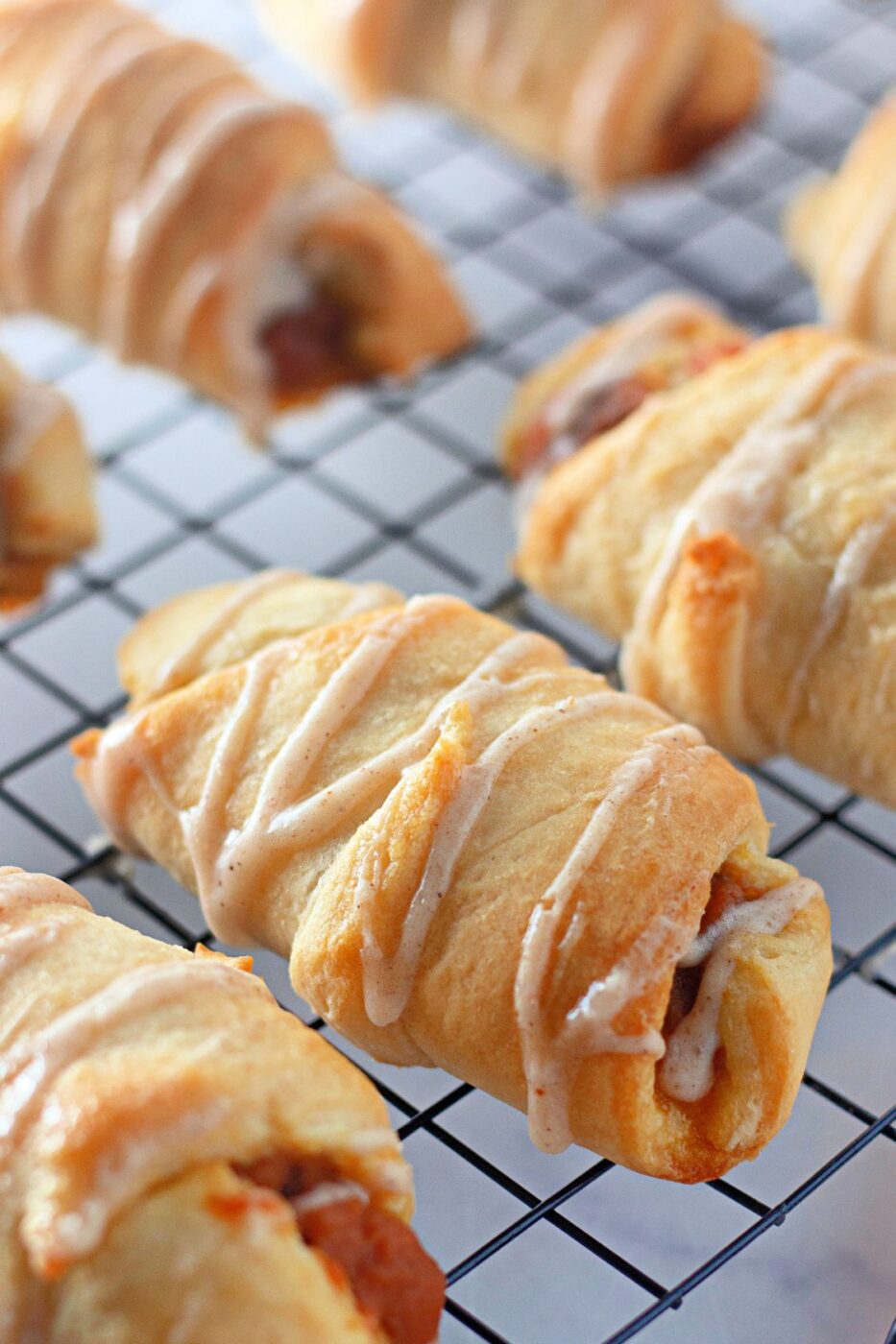 Golden crescent rolls stuffed with pumpkin filling on a baking tray.