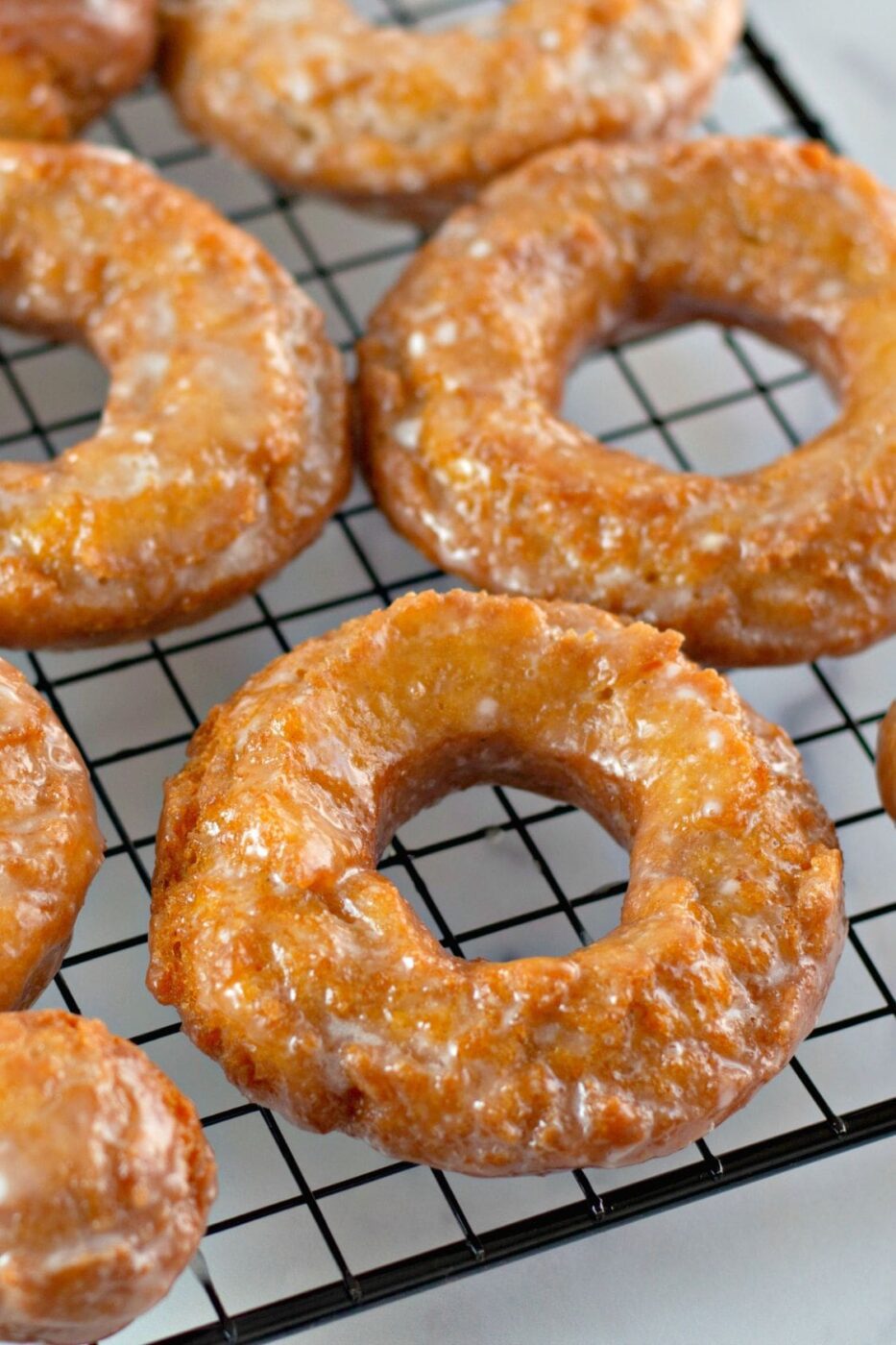 Fresh pumpkin spice donuts stacked and drizzled with glaze.