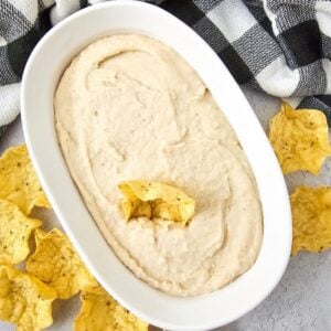 Recipe card image of white bean dip served with scoop-style chips.
