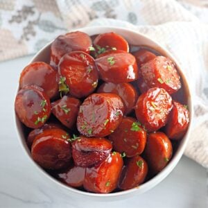 BBQ kielbasa rounds in white dish with rich glaze.