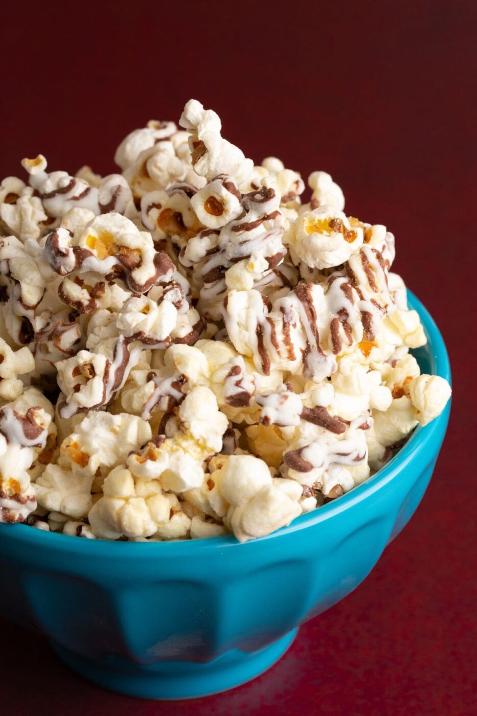 A bowl of popcorn drizzled with white chocolate and fall sprinkles.
