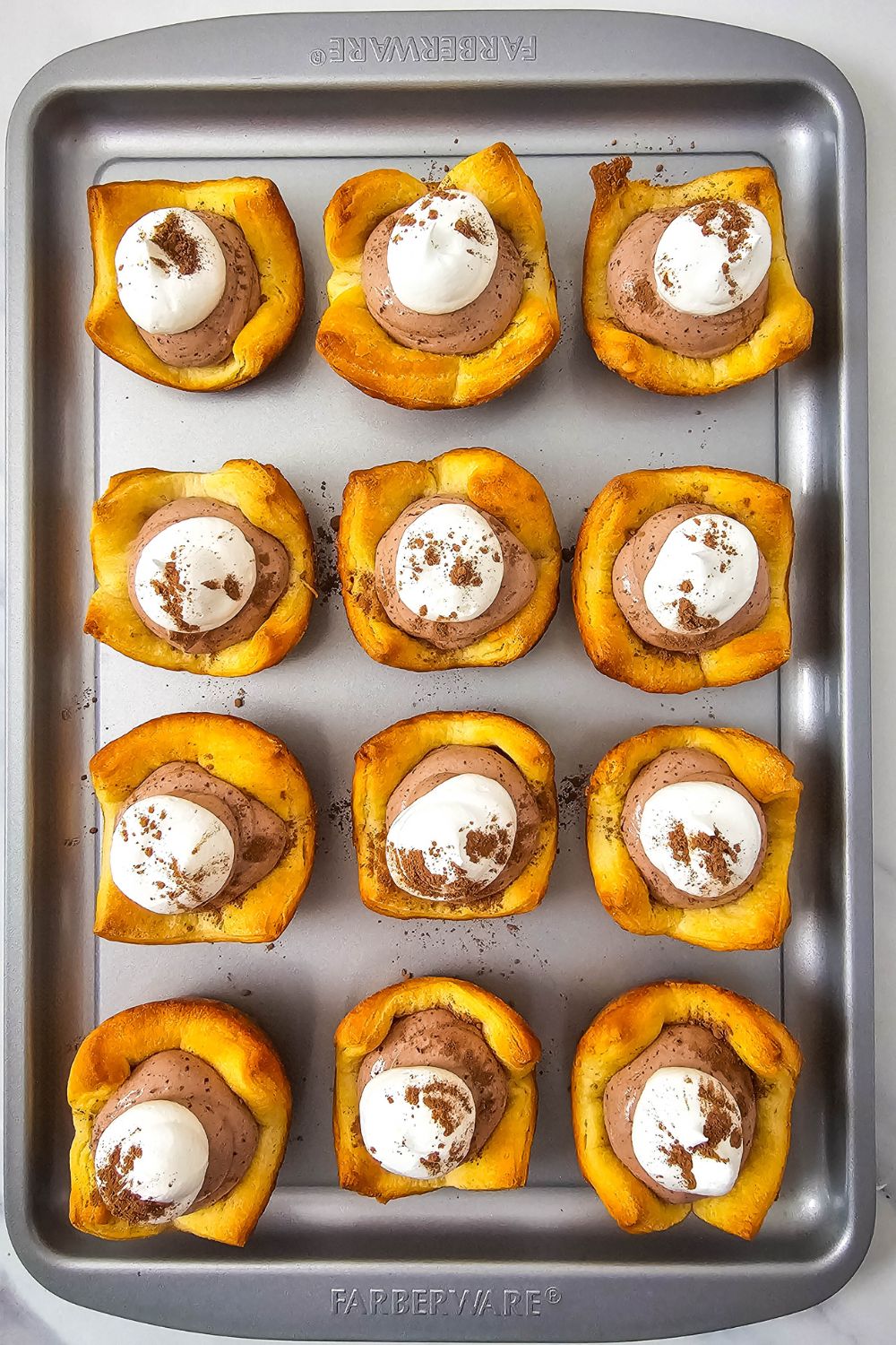 French silk pie bites topped with whipped cream on a baking sheet.