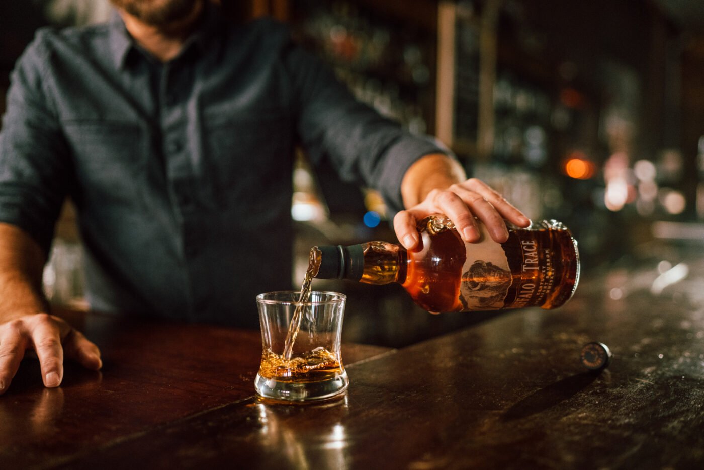A bartender pouring Buffalo Trace bourbon into a glass