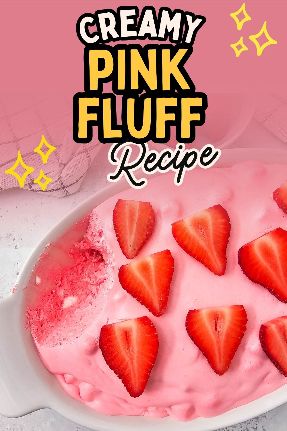 A bowl of creamy pink dessert, strawberry fluff, with whole strawberries on top.