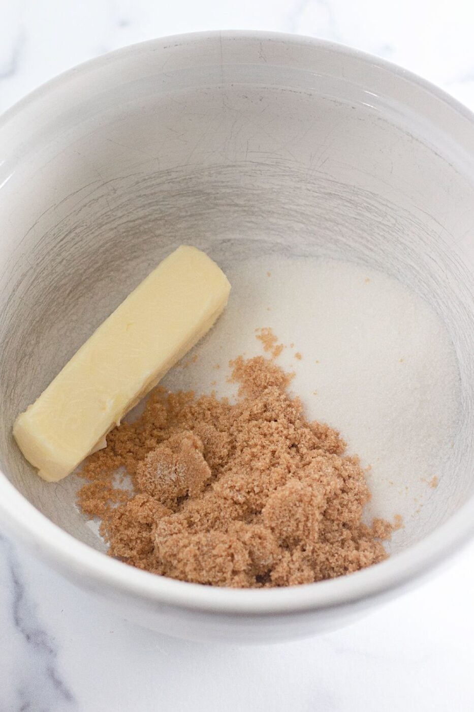 Stick of butter and measured brown sugar and white sugar in a mixing bowl.