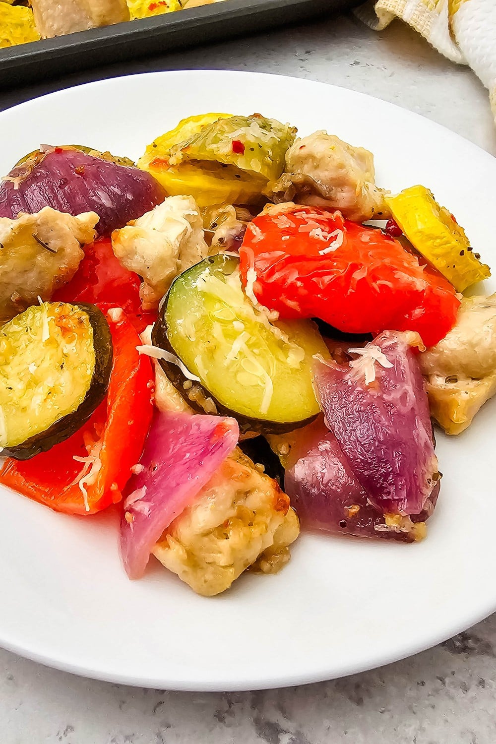 Close-up of finished sheet pan Italian chicken and veggies with melted parmesan