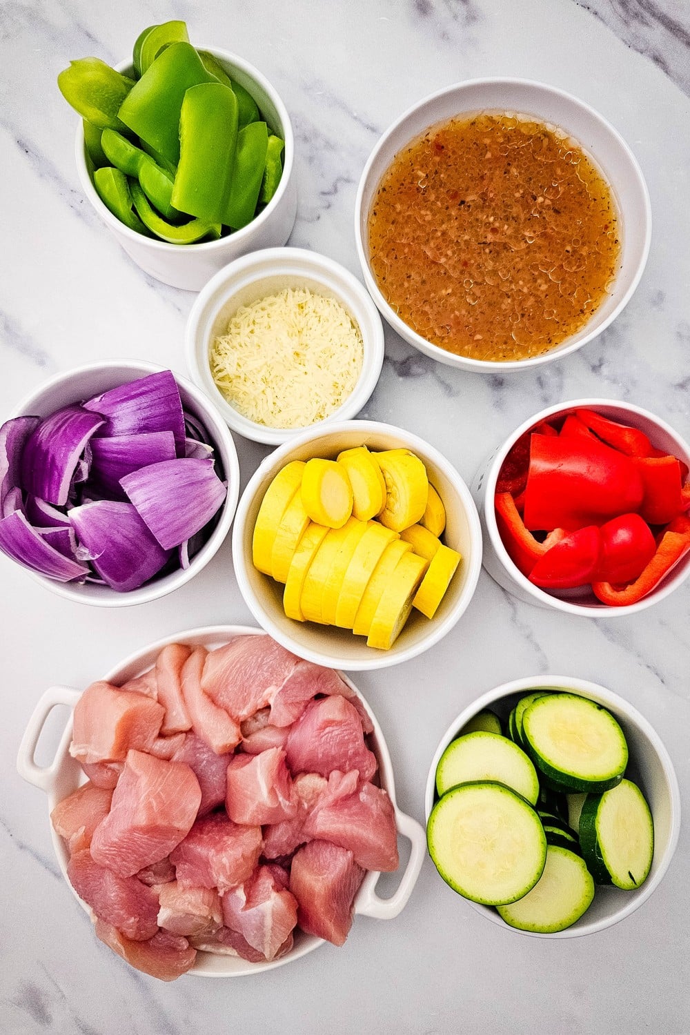 All ingredients for sheet pan Italian chicken and veggies in individual bowls