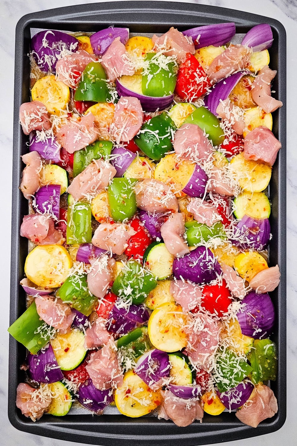 Sheet pan Italian chicken and veggies with parmesan sprinkled before baking