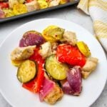 Sheet pan Italian chicken and veggies plated on white dish with roasted vegetables