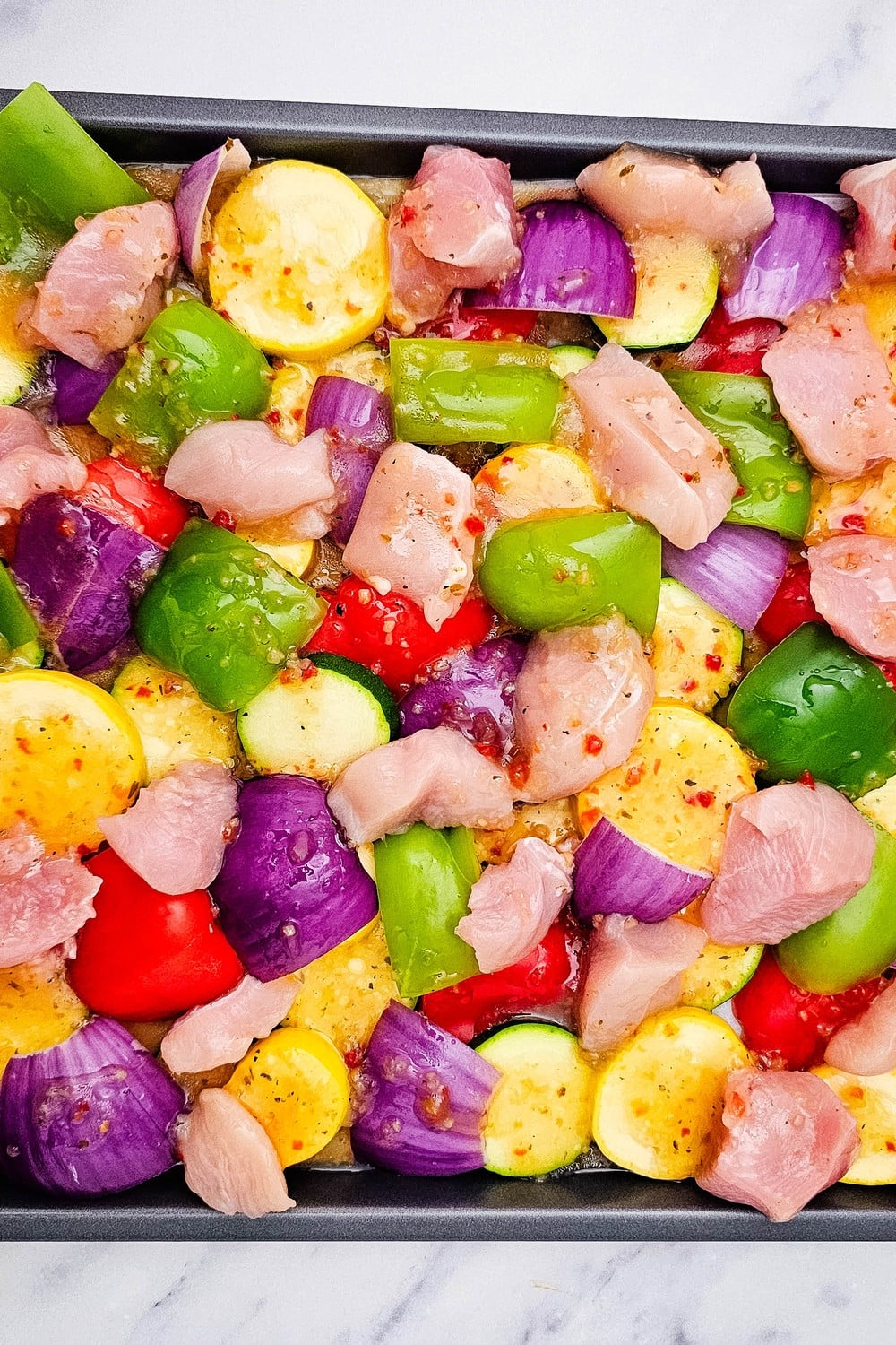 Chicken and vegetables tossed with Italian dressing on sheet pan