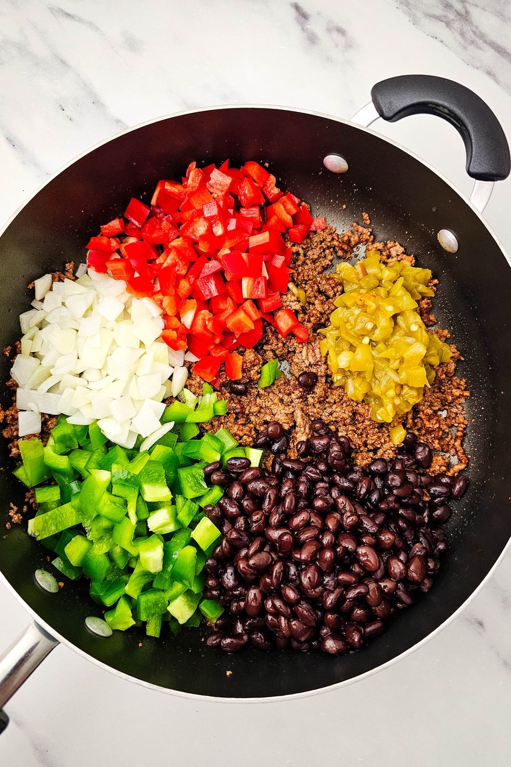 Beef mixture with peppers, beans, and green chilies ready to cook