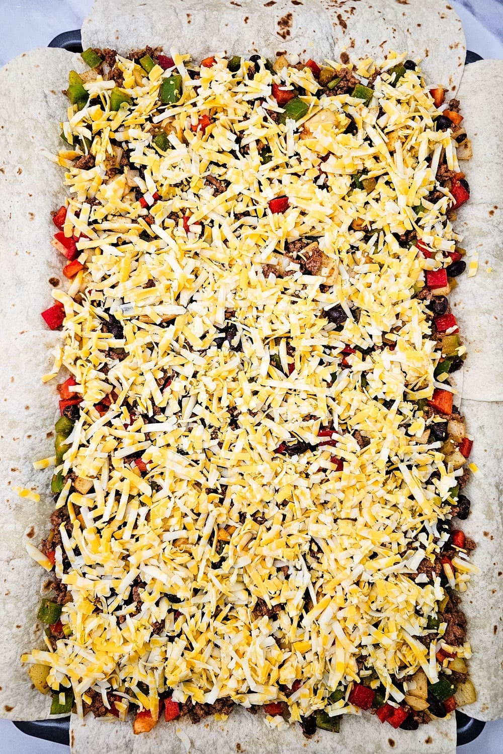 Remaining cheese scattered over the beef filling on the sheet pan