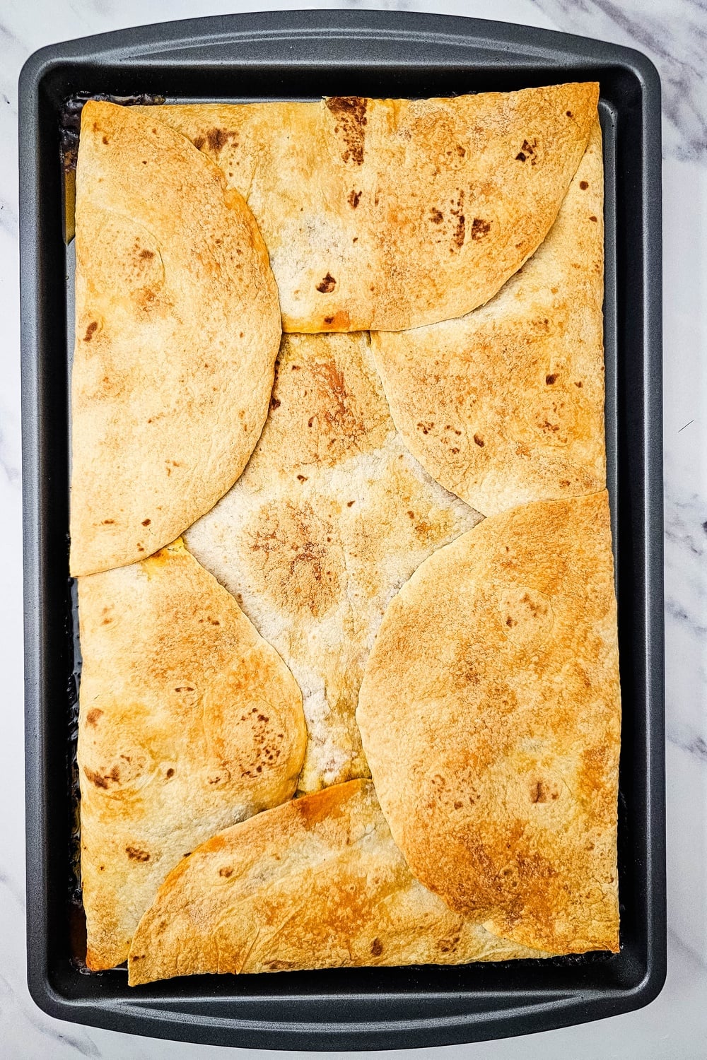Golden baked sheet pan quesadillas after removing the top pan