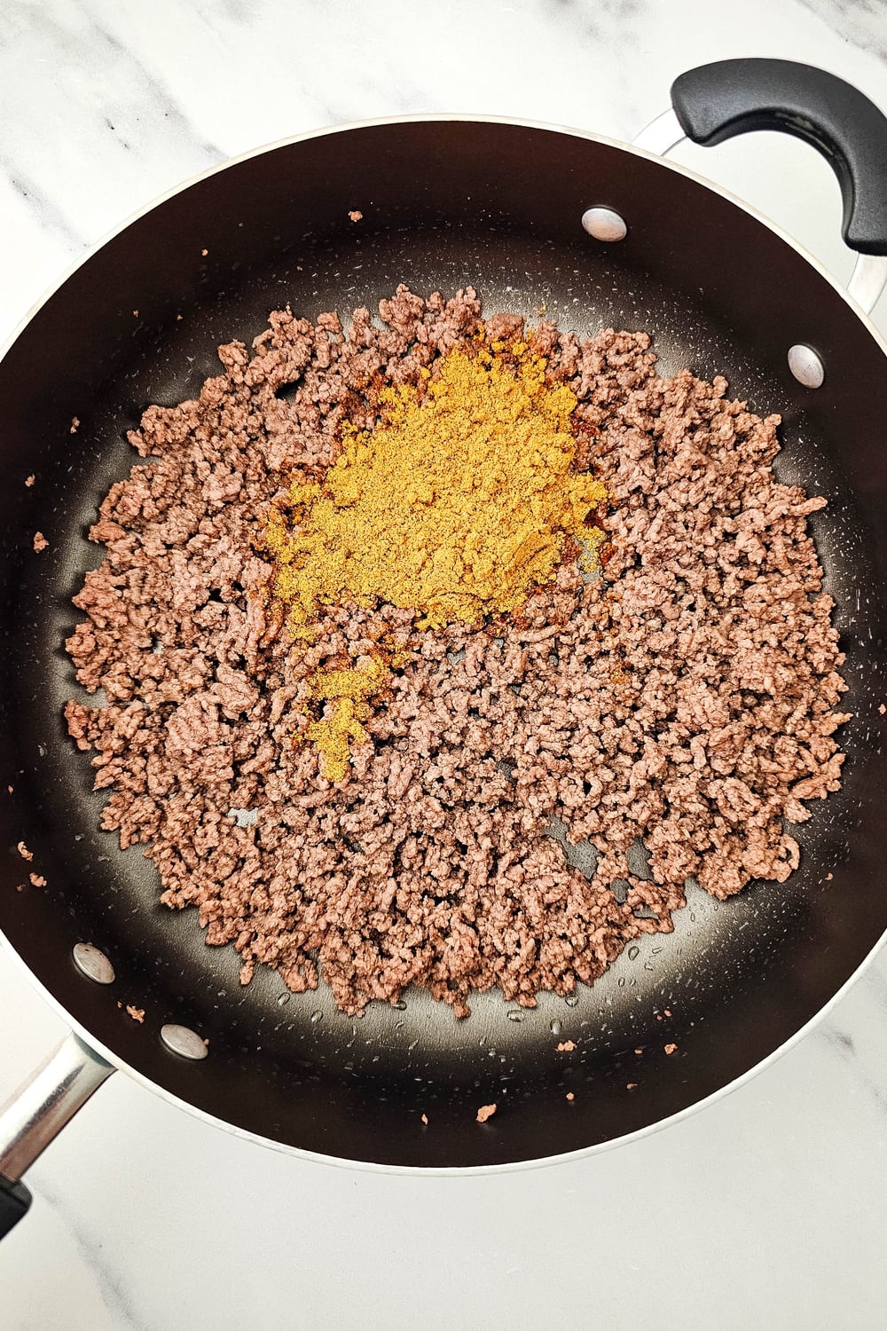 Browned ground beef with taco seasoning in a skillet