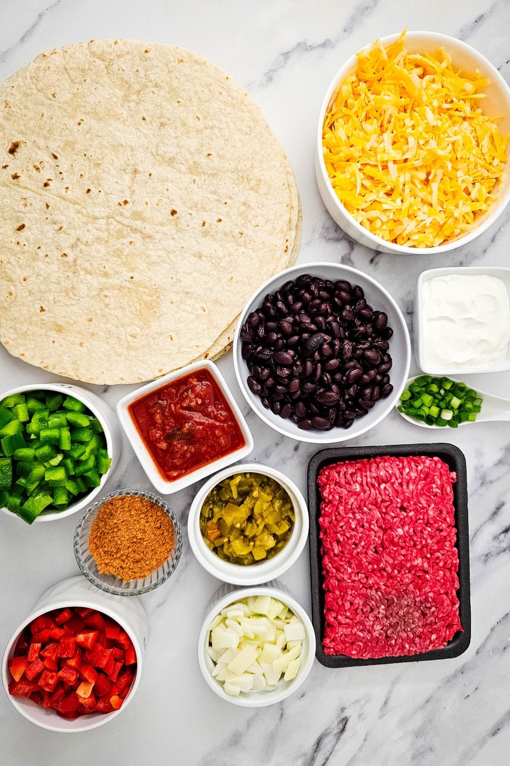 All ingredients for sheet pan tex mex quesadillas laid out on a marble counter
