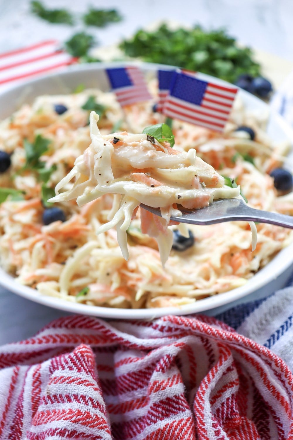 Serving fork lifting a bite of 4th of July coleslaw from a bowl