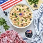 Top-down view of 4th of July coleslaw with blueberries and American flag picks