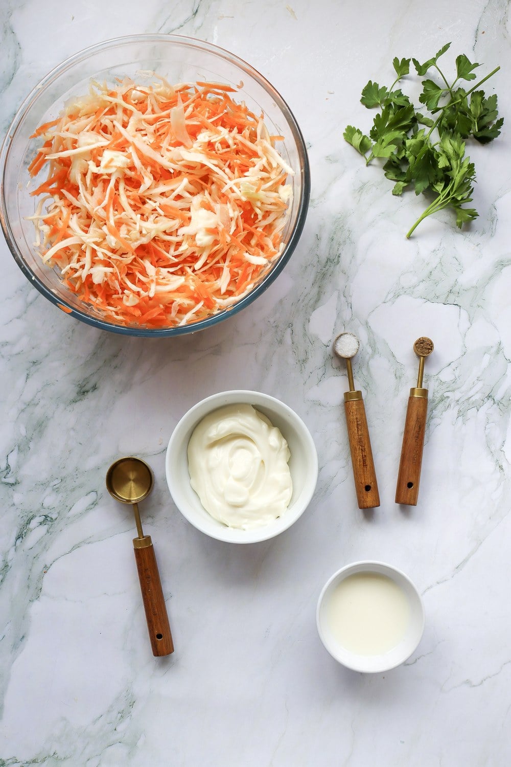 Shredded green cabbage and carrots tossed together in a clear mixing bowl