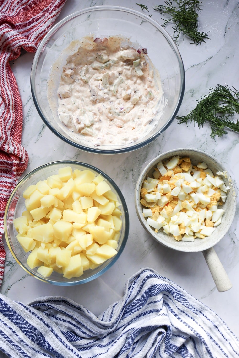 Mise en place for combining 4th of July potato salad: dressing, diced potatoes, and chopped hard-boiled eggs