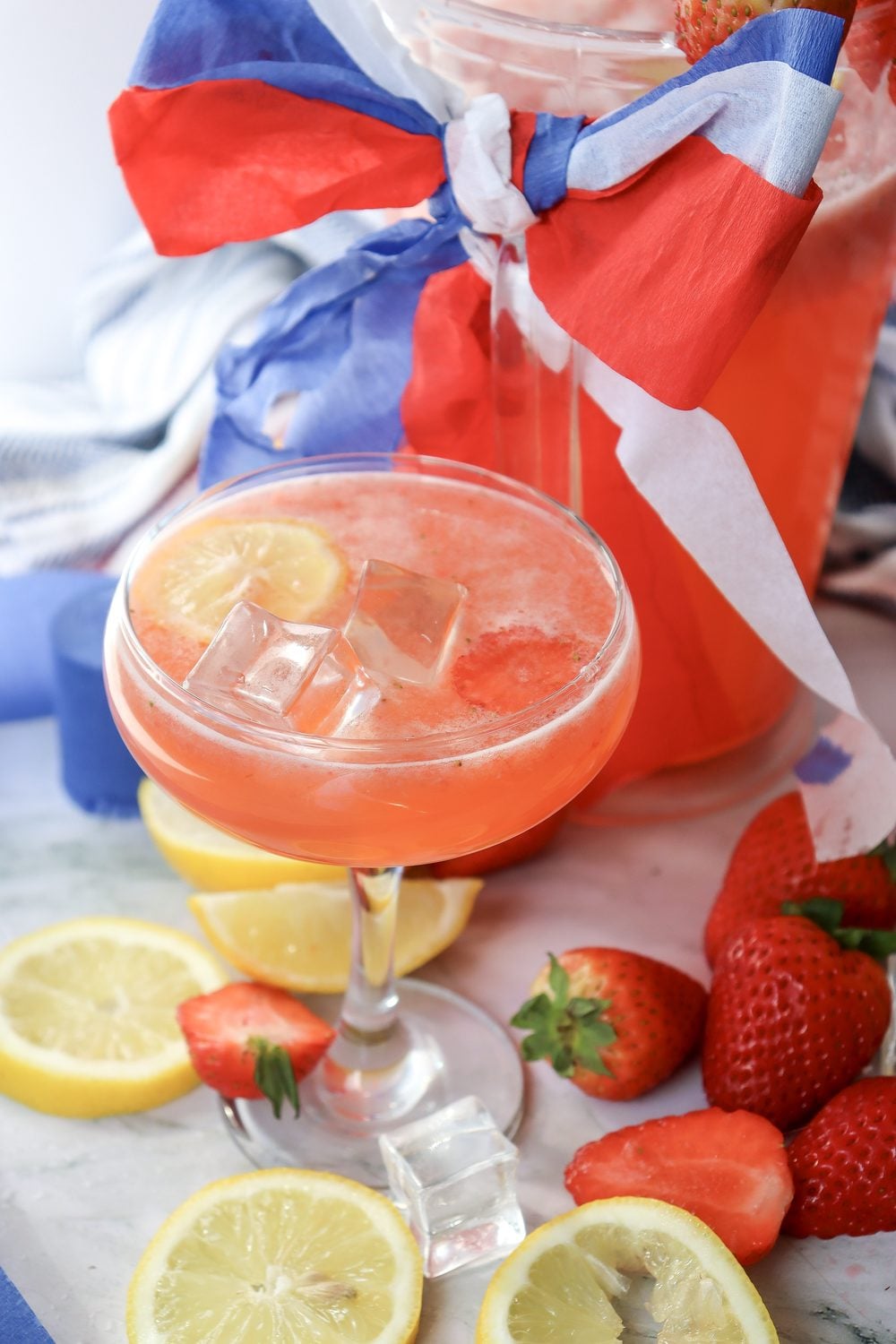 Close-up of a glass of 4th of July strawberry lemonade with ice and a red white and blue ribbon