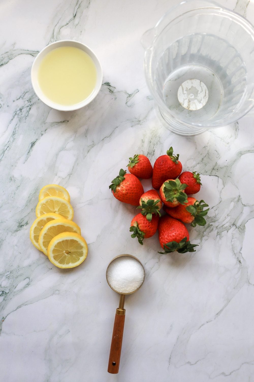 Fresh strawberries, lemons, sugar, and a glass for making 4th of July strawberry lemonade
