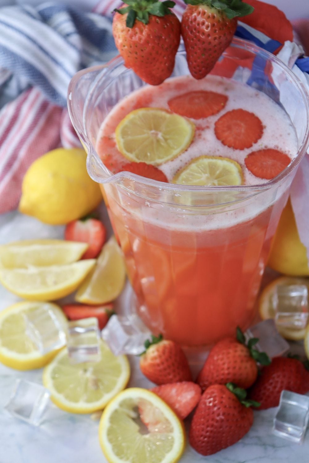 Pitcher and two glasses of 4th of July strawberry lemonade served with ice and patriotic styling