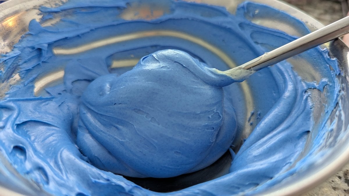 Vibrant blue chocolate coating swirled in glass bowl with spoon