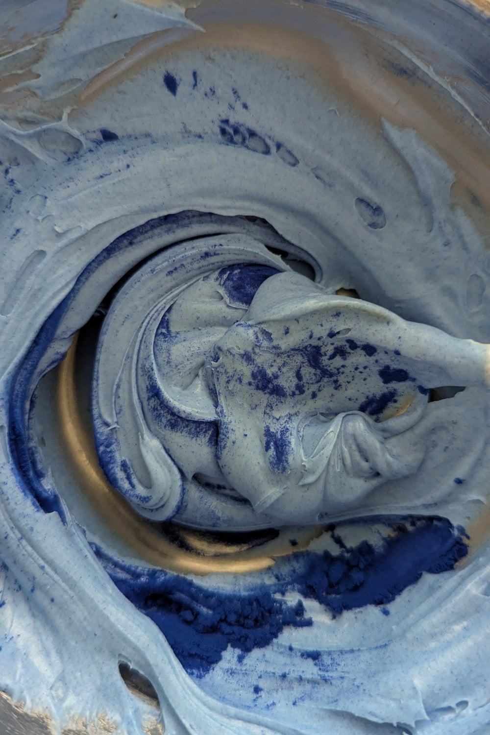 Stirring blue spirulina powder into melted white chocolate to create blue color