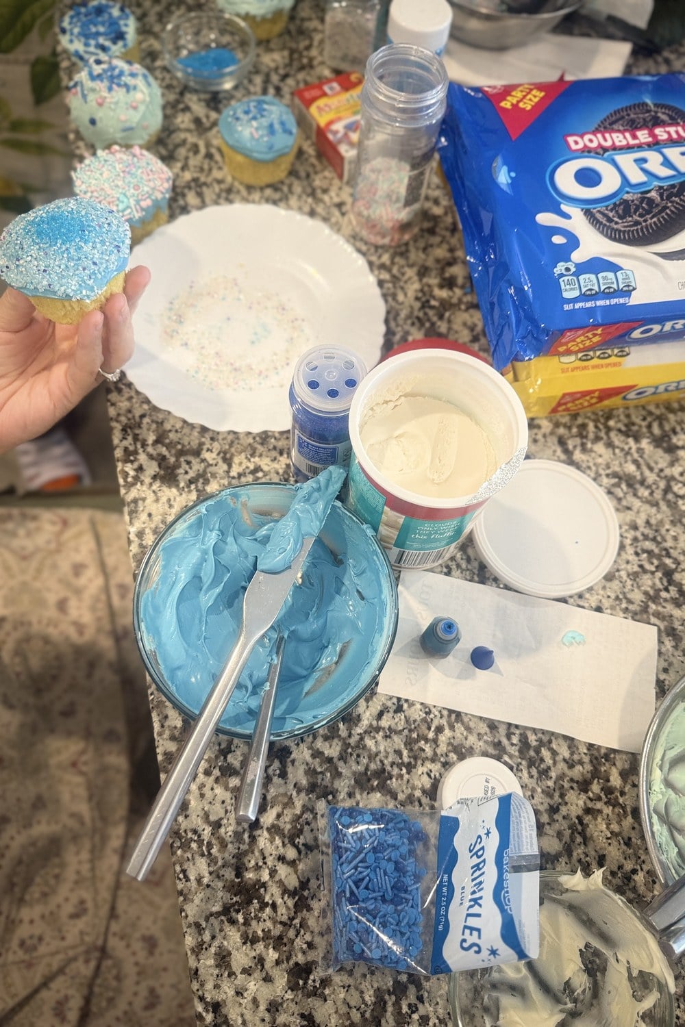 Both methods in progress on a kitchen counter with bowls of tinted frosting, sprinkles, and gel coloring
