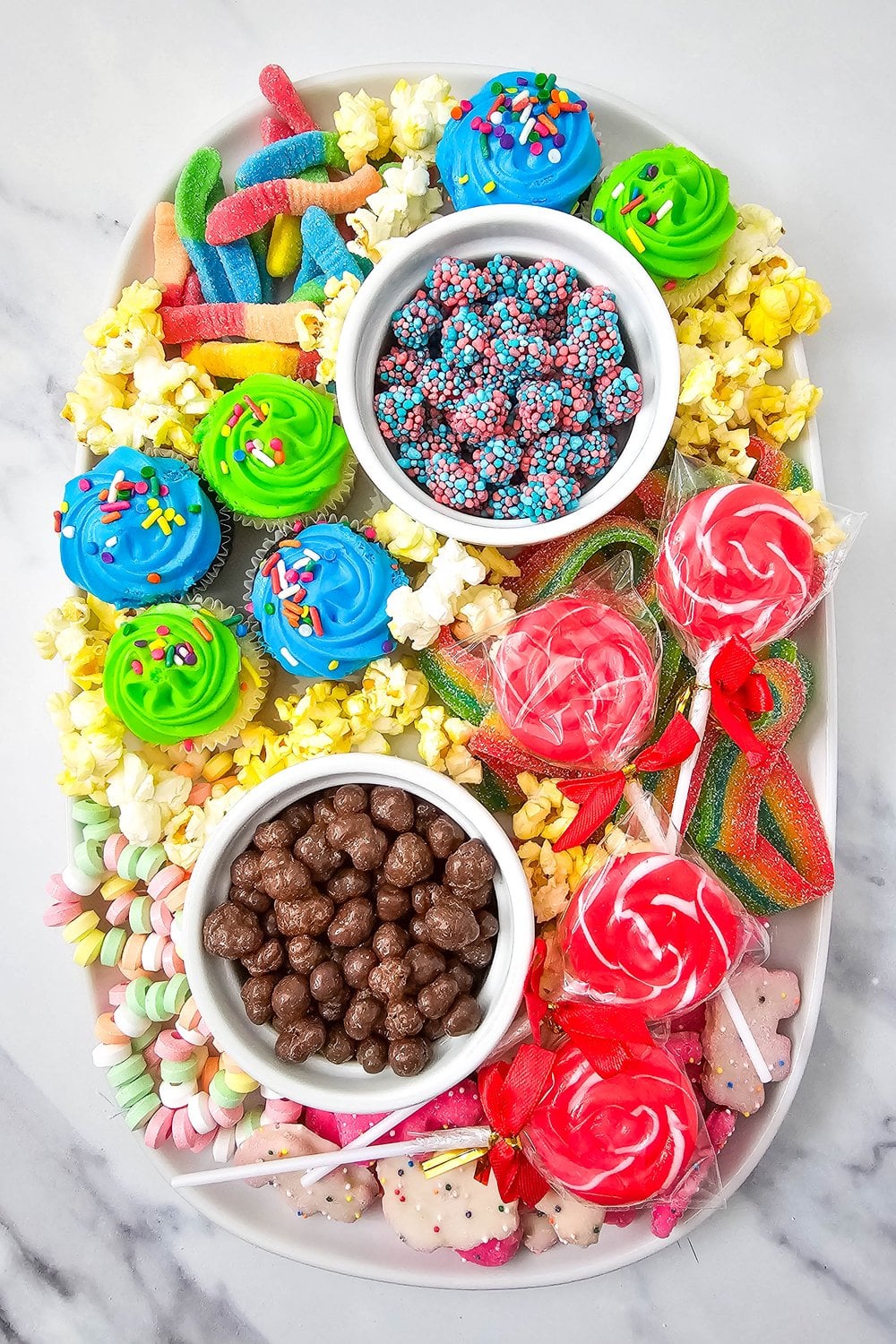Kids birthday charcuterie board with Circus Animal Cookies, mini cupcakes, candy, and popcorn on an oval platter