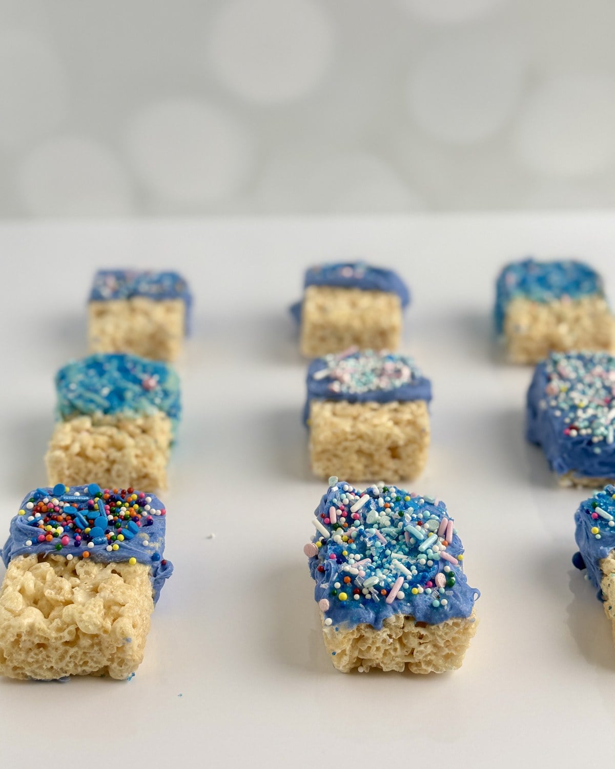 Side view of patriotic rice krispie treats on a white surface with soft bokeh background