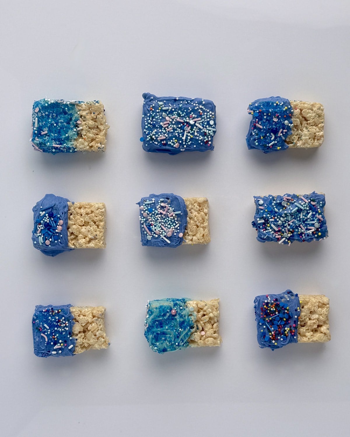 Nine patriotic rice krispie treats laid out in a 3x3 grid showing the range of sprinkle combinations
