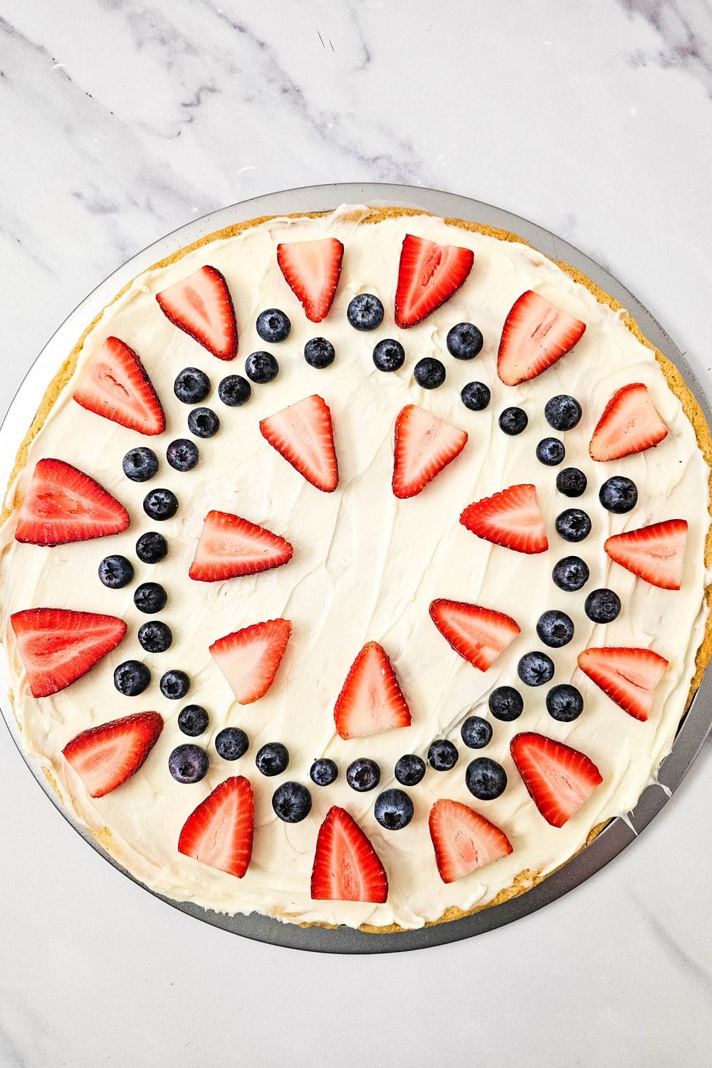 Inner concentric ring of strawberry wedges added inside the blueberry border on a fruit pizza