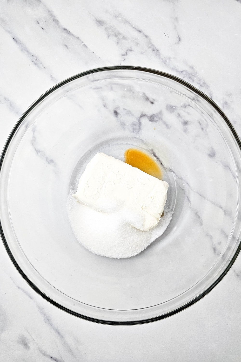 Cream cheese, sugar, and vanilla in a glass mixing bowl before beating, for the cream cheese topping on red, white, and blue fruit pizza