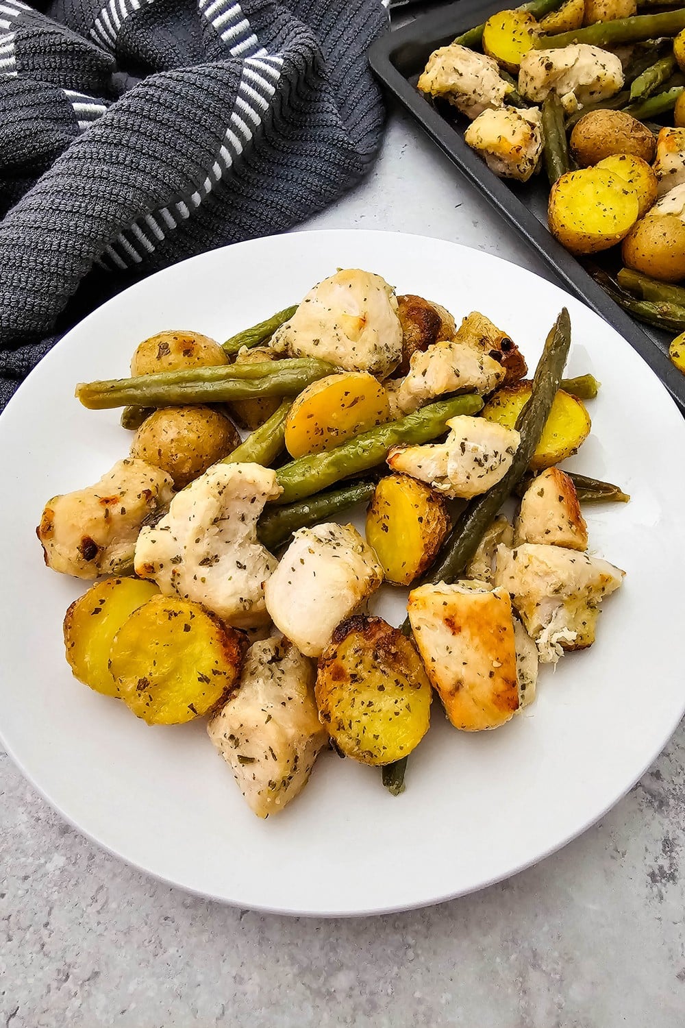 Sheet pan ranch chicken and veggies plated with golden chicken cubes, halved baby potatoes, and ranch-flecked green beans.