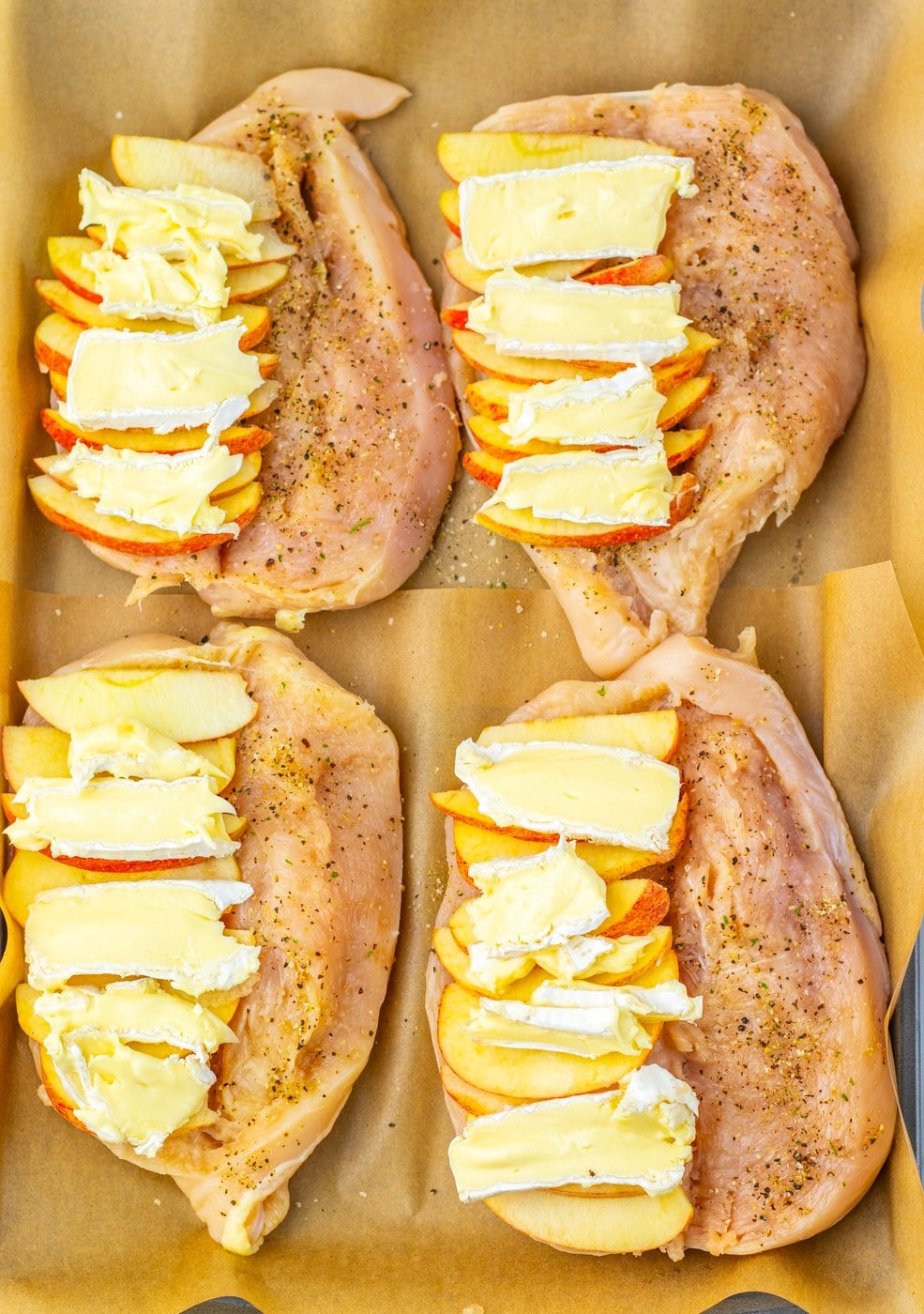 Sliced apples and brie cheese layered inside butterflied chicken breasts