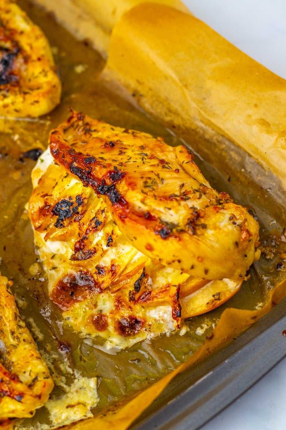 Baked apple and brie stuffed chicken on a parchment-lined tray