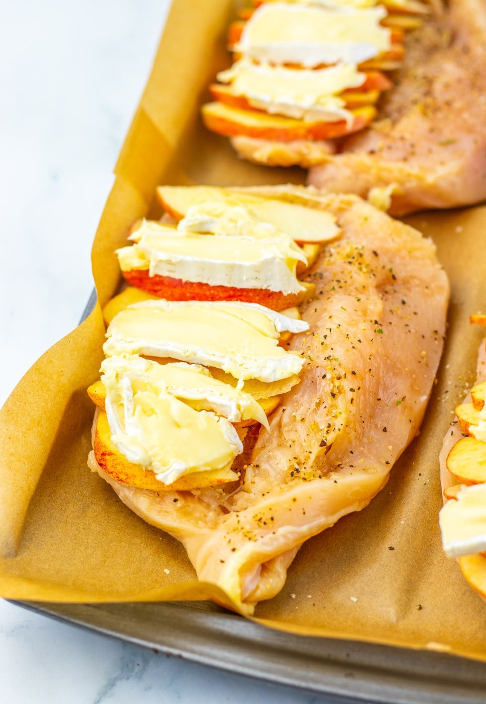 Chicken breasts stuffed with apple and brie on a baking sheet