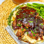 Apple cider glazed pork chops with apple cider in the background