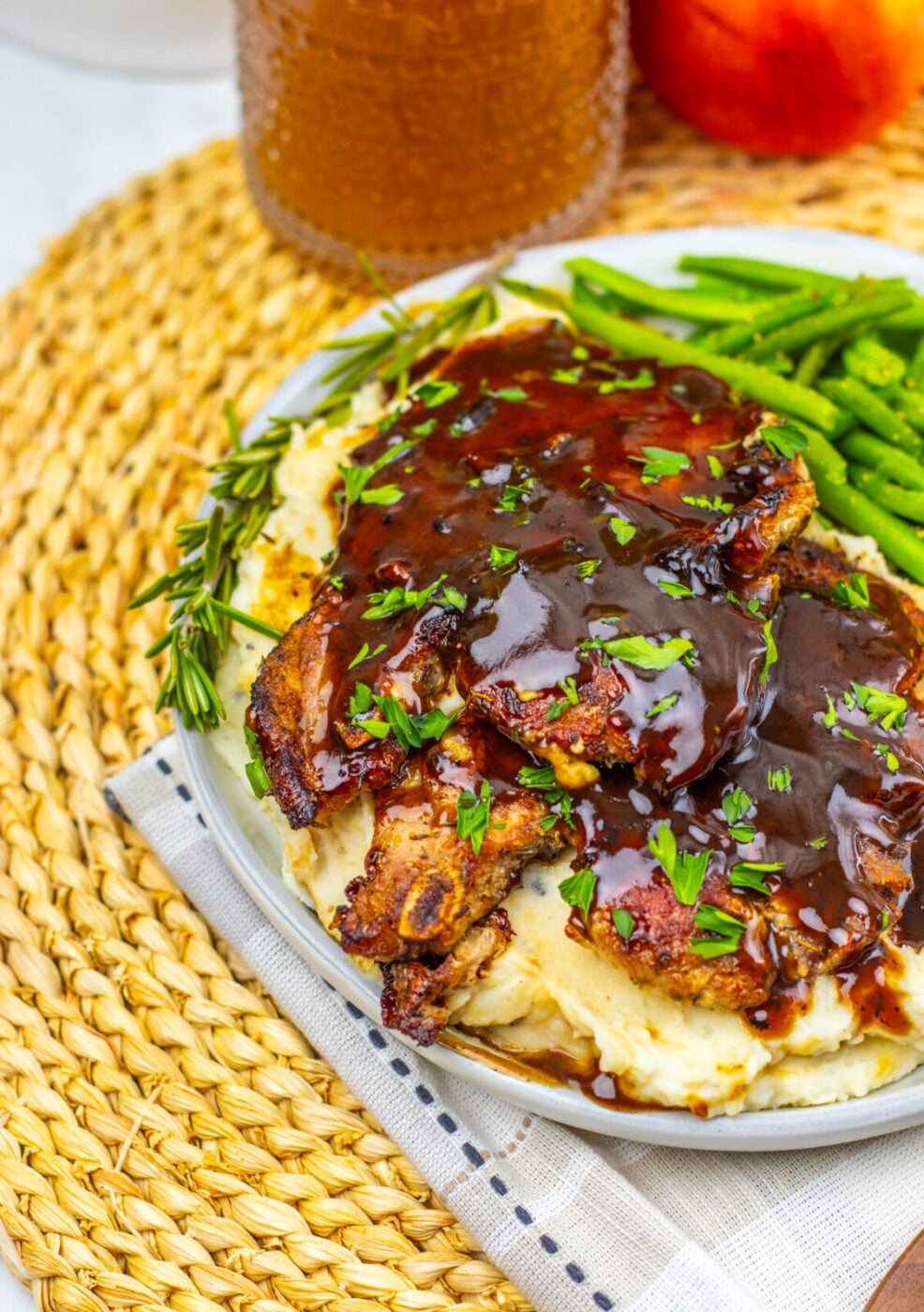 Apple cider glazed pork chops with apple cider in the background
