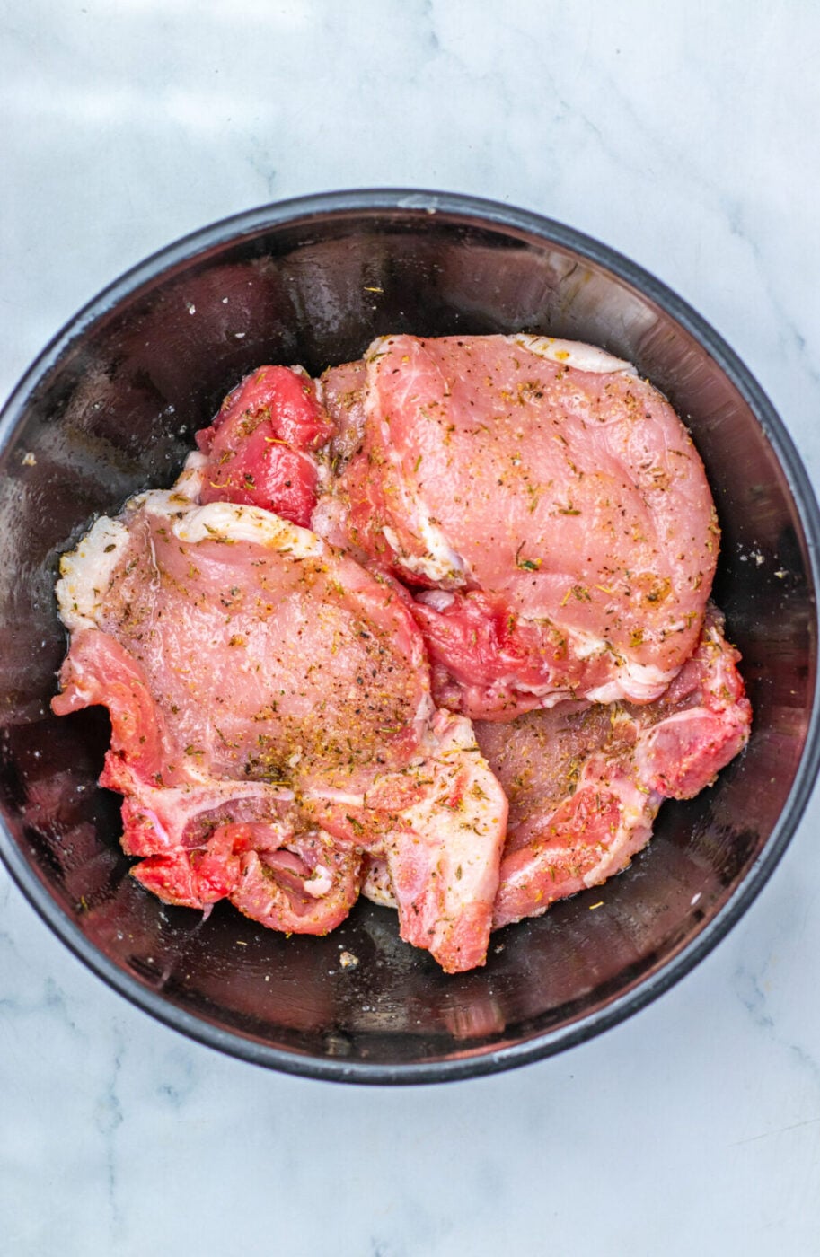 Seasoned pork chops coated and ready to sear