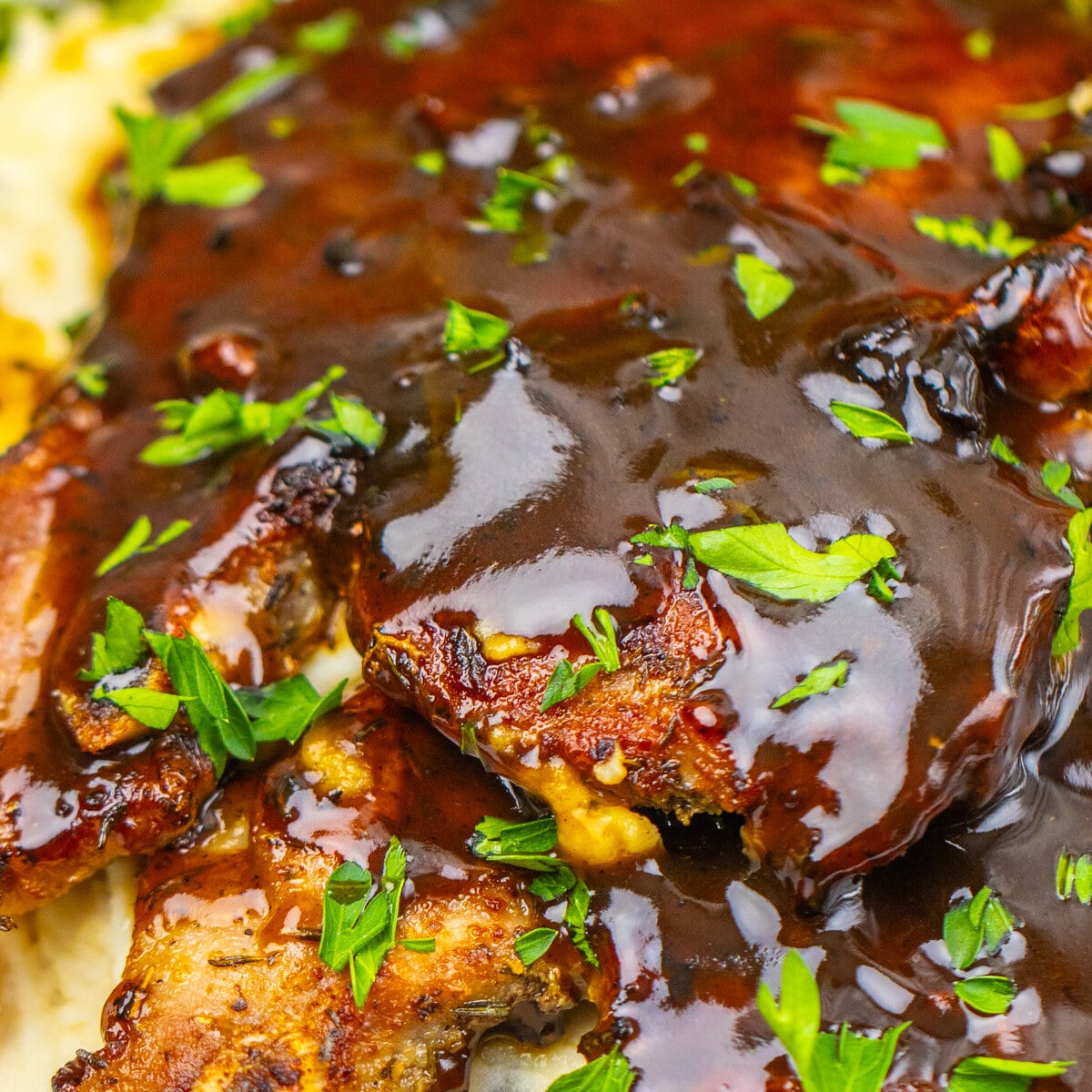 Close-up of apple cider glazed pork chops with glossy cider glaze and fresh parsley