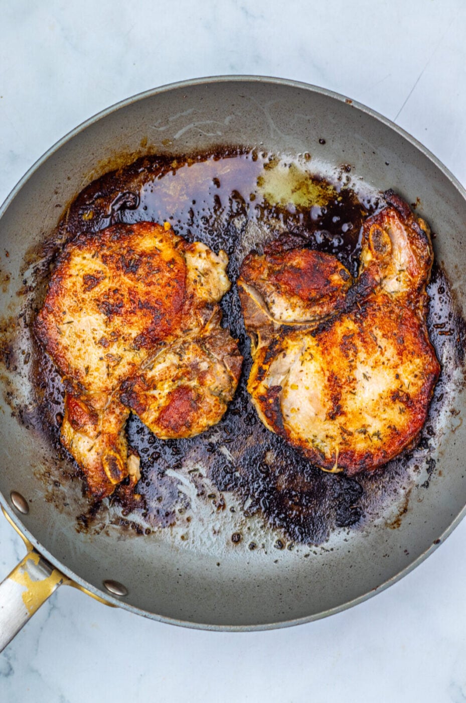 Pork chops seared golden brown in a skillet