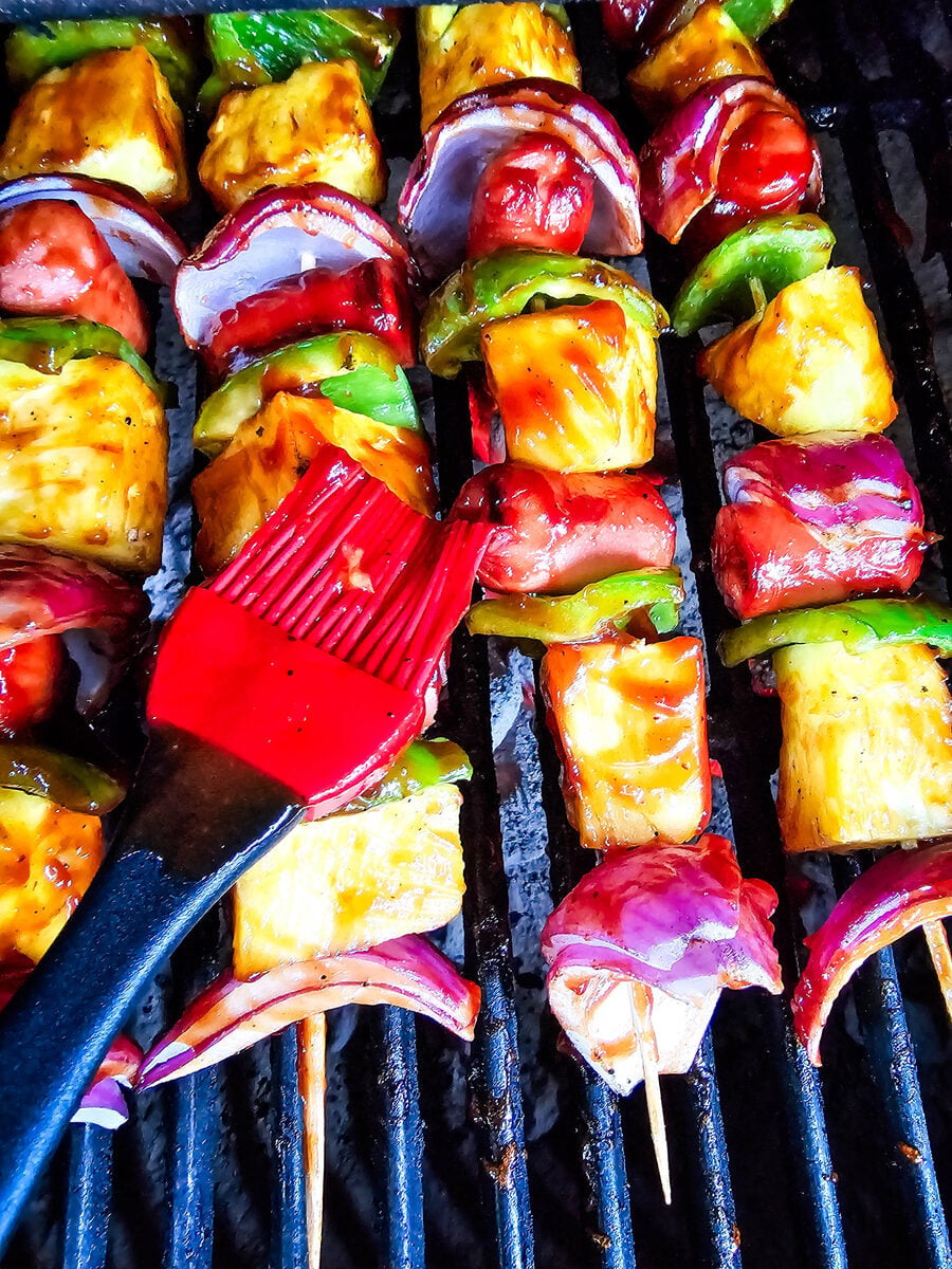 Brushing barbecue sauce on hot dog kabobs on the grill