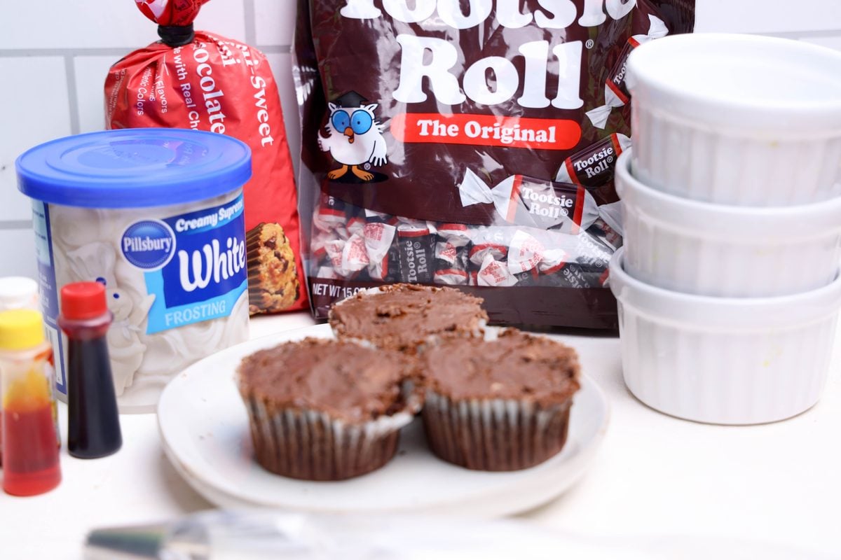 Ingredients for campfire cupcakes: chocolate cupcakes, Tootsie Rolls, frosting, food coloring, and mini chocolate chips